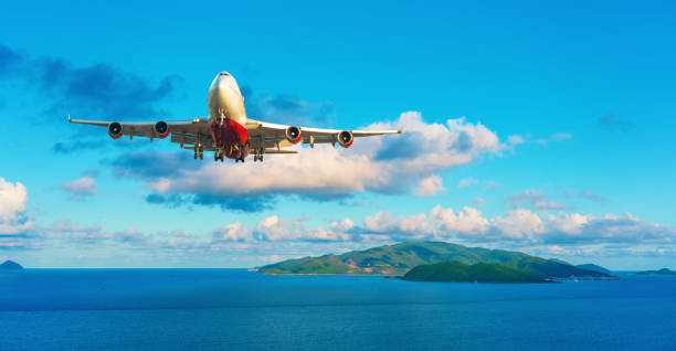 Plane fly ready for landing approaching over ocean and bay island tropical exotic jungle.