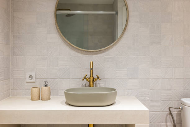 istock Oval stylish sink on white smooth marble countertop in modern bathroom. Copper-colored two-valve faucet blends harmoniously with round mirror hanging on tiled wall 2188678895