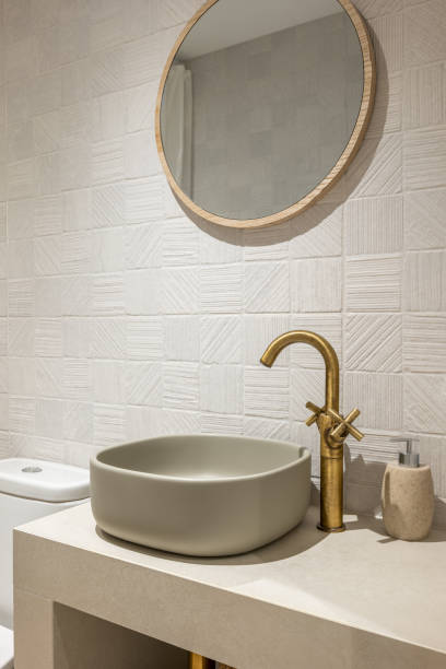 istock Neat stylish oval-shaped sink on white marble countertop with an elegant copper-coloured faucet. Above sink hangs a round modern gold-framed mirror. 2188678920