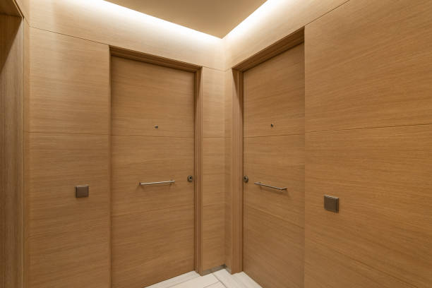 istock Soft light from niche under ceiling illuminates doors and walls in common corridor. Interior is made in same style of precious wood. Entrance doors are equipped with bell and door peephole. 2188679022