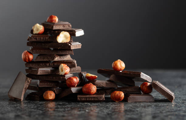 istock Broken dark chocolate bar with hazelnuts on a black background. 2188681247