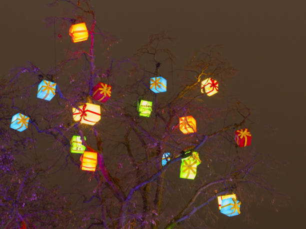 Outdoor ornated Christmas tree with hanging illuminated present gift boxes