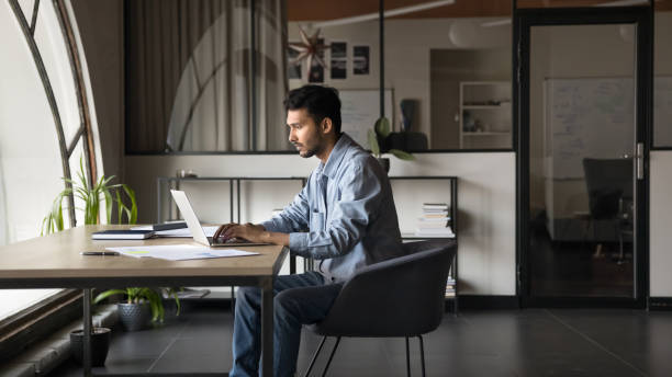 istock Serious Indian businessman sitting at desk, working on laptop 2188687721