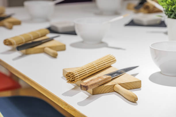 Set of knife, board and bamboo sushi mat on white table before sushi master class. Education, cooking and entertainment concept