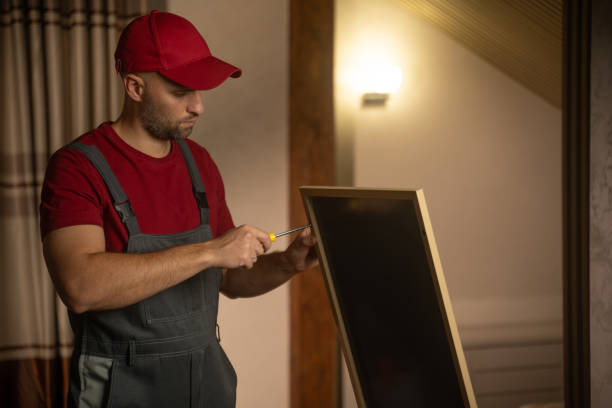 Repairman works on fixing a broken mirror in a cozy interior setting during daytime stock photo