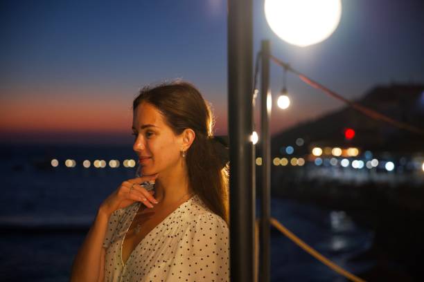 istock Woman Reflecting at Sunset with Ocean Lights and Warm Evening Glow 2188691168