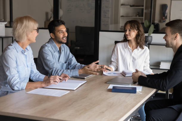 istock Group of four professionals engaged in meeting around conference table 2188691944