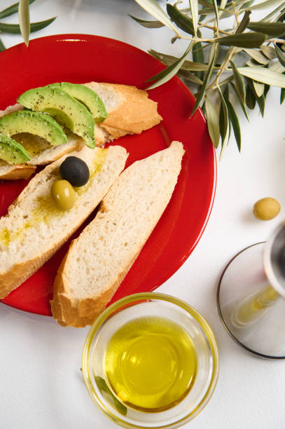 istock Fresh baguette with avocado and olives on a vibrant red plate 2188692184