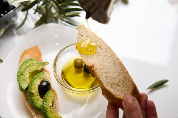 istock Pouring olive oil on fresh bread slice with avocado and olives 2188692337
