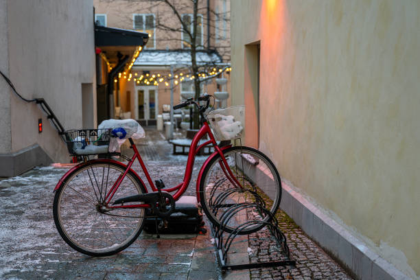 Red bicycle with a basket parked on backyard adorned with warm festive string lights. Winter concert