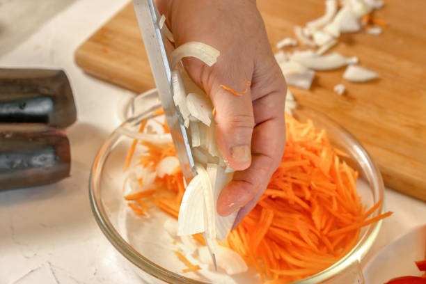 istock Chef adds chopped onion to grated carrots. Close-up 2188695609