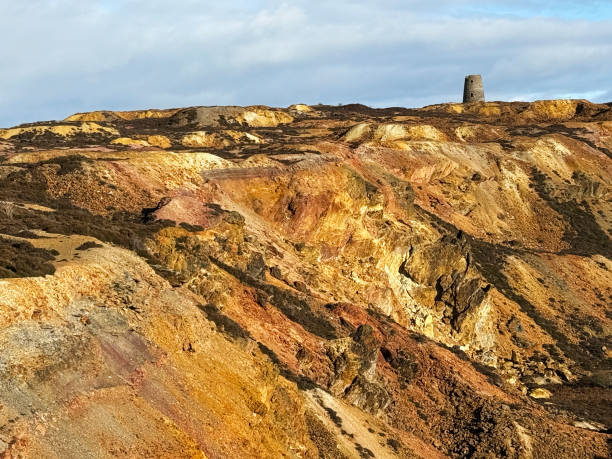 Extraordinary colours of copper in disused and ancient copper & zinc mine known as Parys Mountain on Welsh island of Anglesey. An old windmill used to vent the mine shafts is on the horizon. Open to the public without payment.