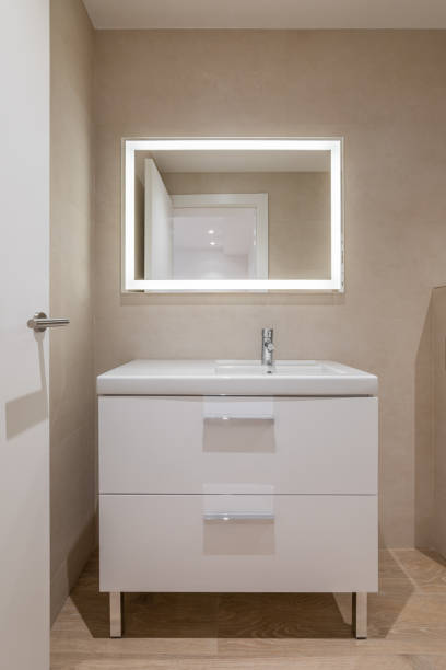 istock Modern bathroom with beige tiles, furniture and rectangular large mirror with lighting 2188701323