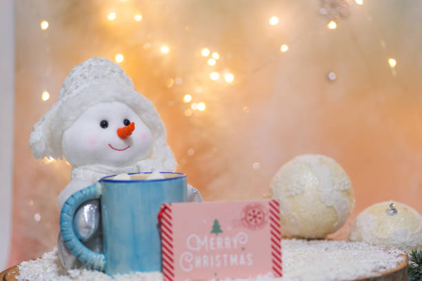 A cheerful snowman toy with a cozy mug of hot cocoa set in a warm and inviting Christmas ambiance, surrounded by twinkling lights and soft decor elements.