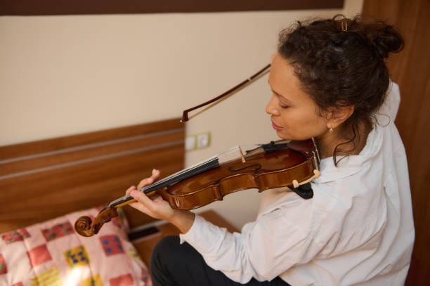 istock Woman practicing violin in a cozy bedroom with a colorful pillow 2188708497