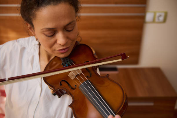 istock Woman plays violin passionately in a warm, inviting room 2188708616