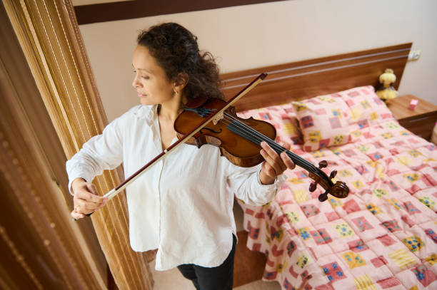 istock Young woman playing violin in cozy bedroom setting 2188708634