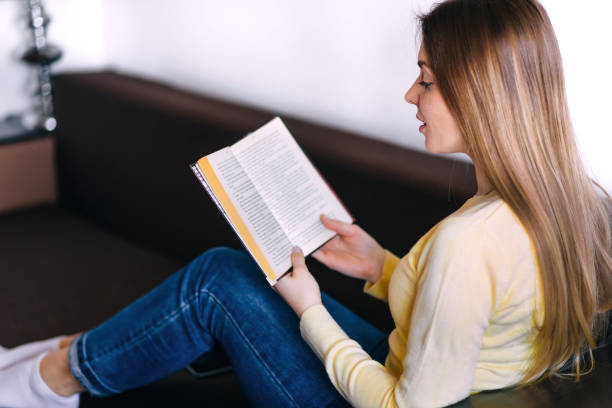 istock woman lying on sofa and reading book at home 2188727876
