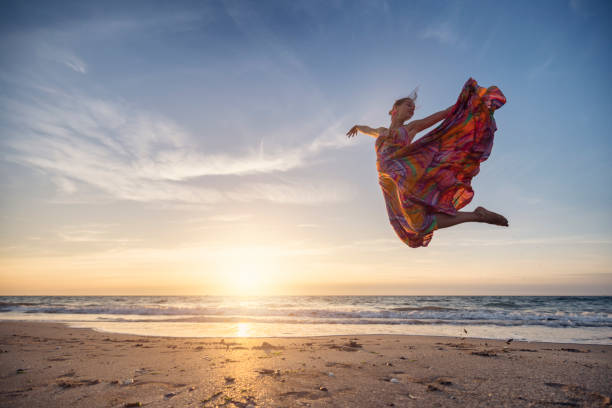 istock Young woman leaping gracefully on a wide, sandy beach at sunset 2188735484