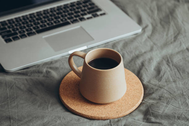 istock Espresso coffee in brown ceramic cup on grey bed with laptop. 2188737120