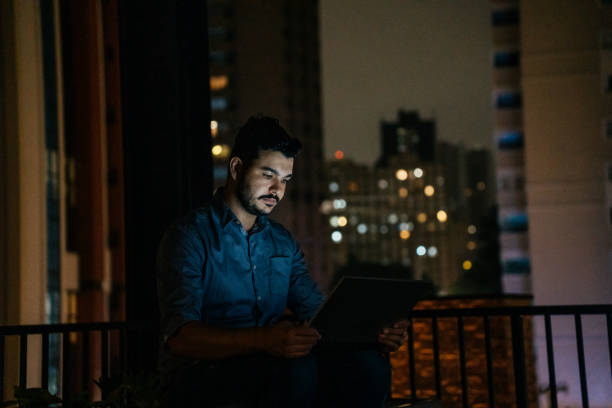 istock Man looking at laptop at night on terrace 2188746781