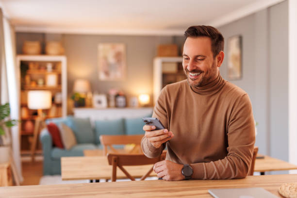 istock Portrait of handsome freelancer smiling and texting over mobile phone while working in home office 2188754683
