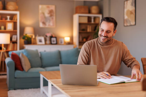istock Portrait of successful businessman analyzing reports over laptop while working at desk in living room 2188754788