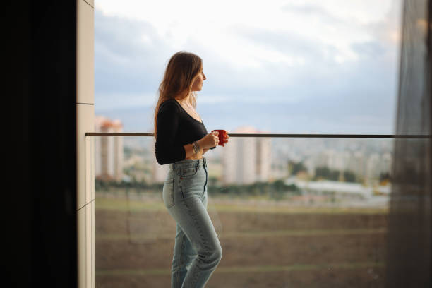 Woman Having Coffee While Standing At Balcony