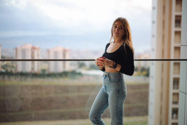 Woman Having Coffee While Standing At Balcony