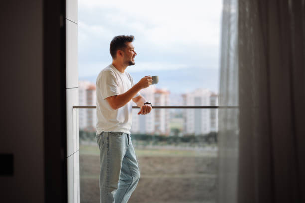 istock Man holding coffee cup while looking away at home 2188756932
