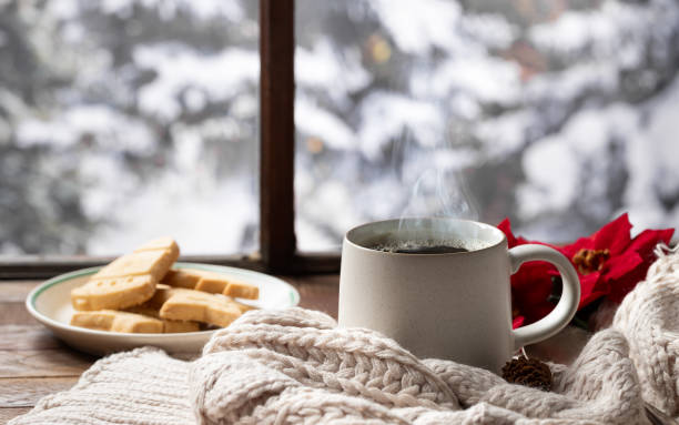 istock Steaming cup of coffee and blanket with snowy winter background 2188757155