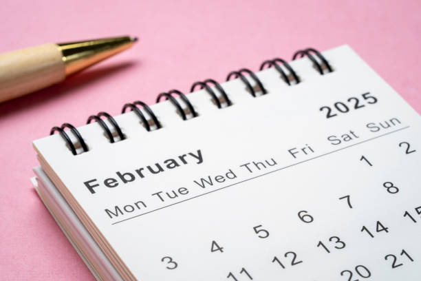 February 2025 - small spiral desktop calendar with a pen, time and business concept