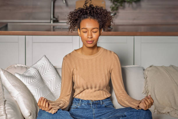 istock Relaxed Woman Meditating at Home sitting on sofa 2188758079