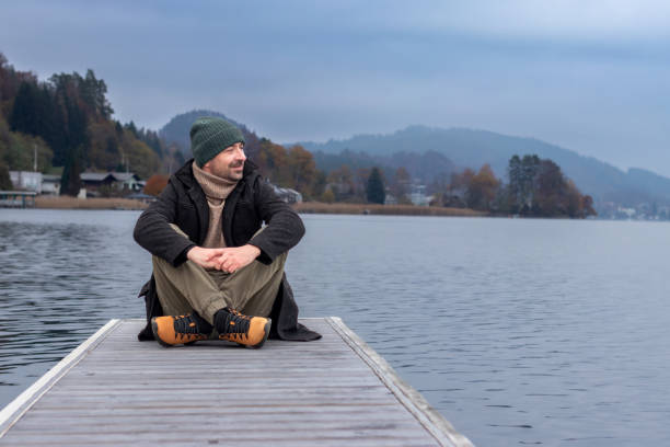 Man sitting on wooden deck pier at Worthersee lake Austria