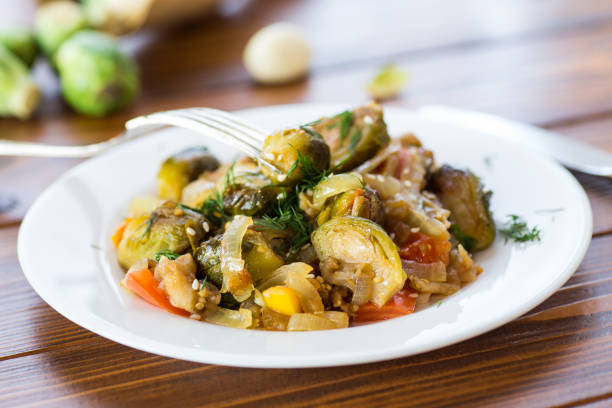 istock Brussel sprouts cooked with vegetables and spices, on a wooden table 2188759854