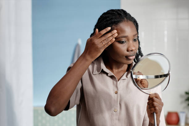 istock Black Woman Applying Makeup while Holding Mirror in Bathroom 2188762084