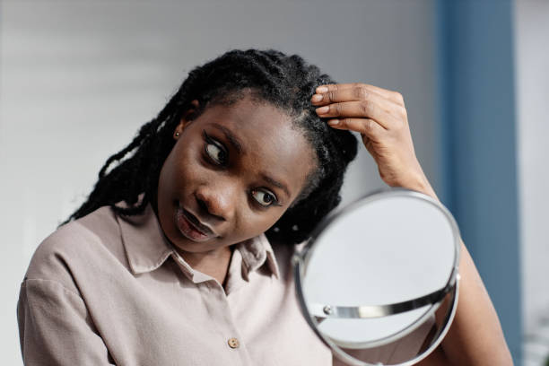 istock Black Woman Touching Hair Scrutinizing Reflection in Mirror during Self Care Routine at Home 2188762088