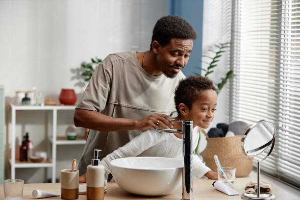 istock Father and Son Looking in Mirror Sharing Skin Care Routine in Bathroom 2188762110