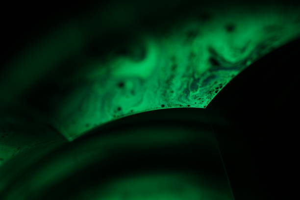 Reflections of liquid in macro, green liquid surface, bubbles in macro, connection of bubbles in macro, cell from liquid, dark background, glossy light