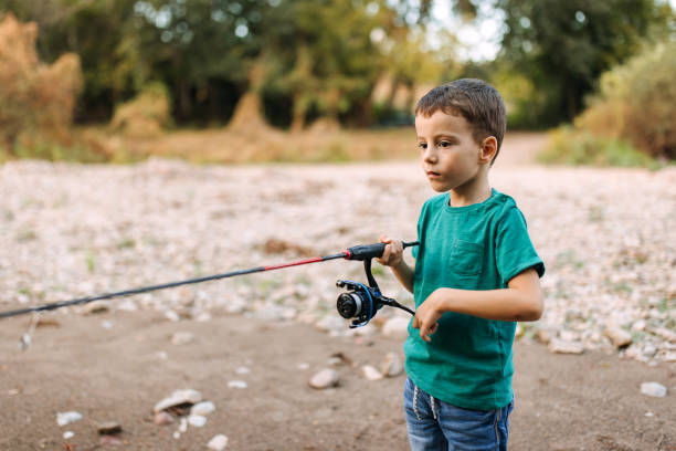 A boy is fishing alone from the shore.