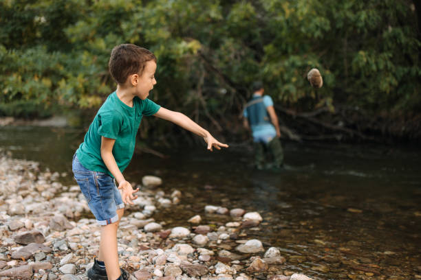 istock Boy throws stones into the water. 2188771162