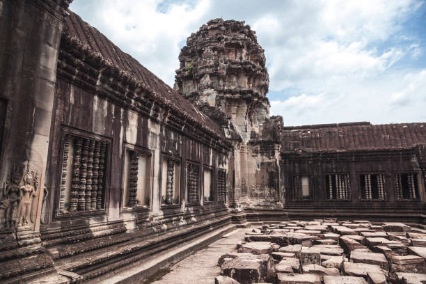 Explore the intricate stone carvings and towering structures of Angkor Wat, a UNESCO World Heritage site in Cambodia. Witness the artistry and grandeur of this historic site under a cloudy sky.