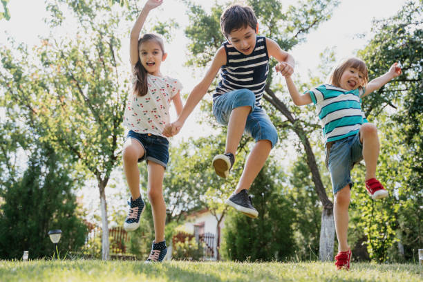istock Kids jumping joyfully in grassy garden sunshine 2188774165
