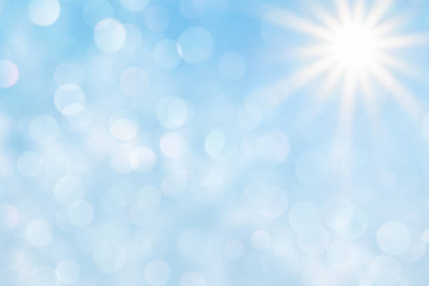 Bright sun with beautiful beams and bokeh light in the blue sky. Space for copy.