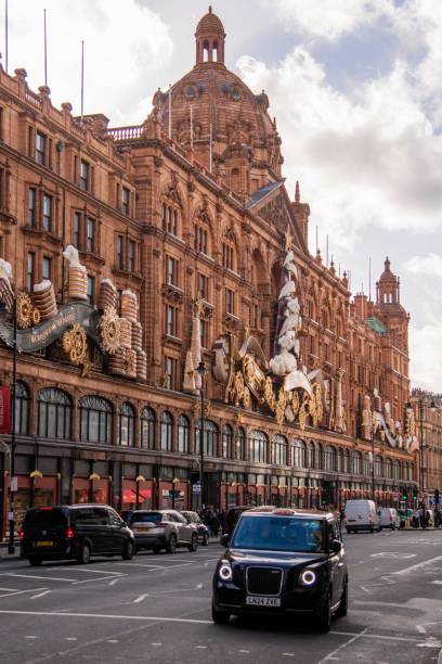 London, United Kingdom - November 25, 2024: Black Cab passing by Christmas Decorations by Loro Piana on Harrods