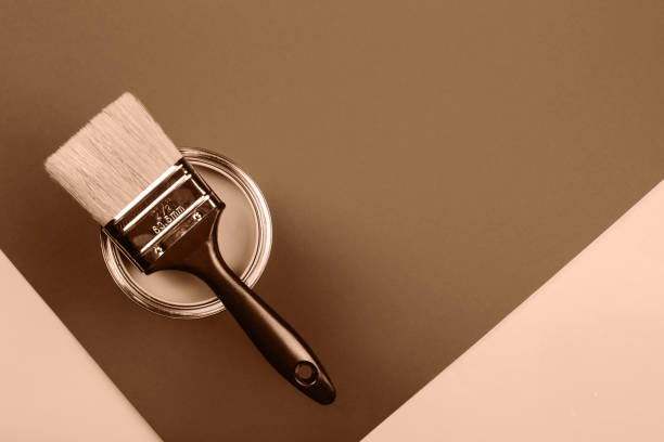Paintbrush resting on a can against a mocha and mousse background