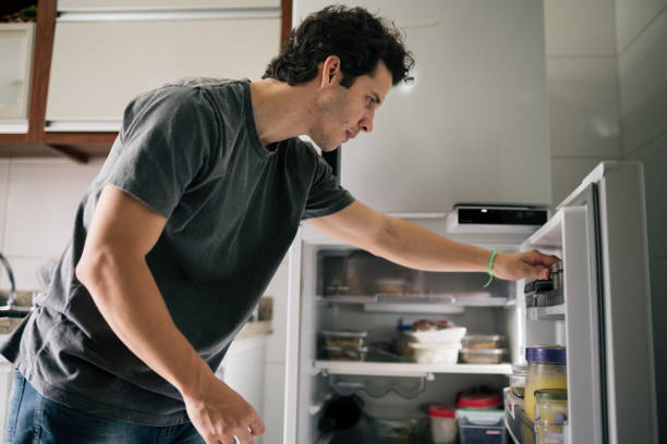 istock Young man opening the fridge and choosing something 2188791384