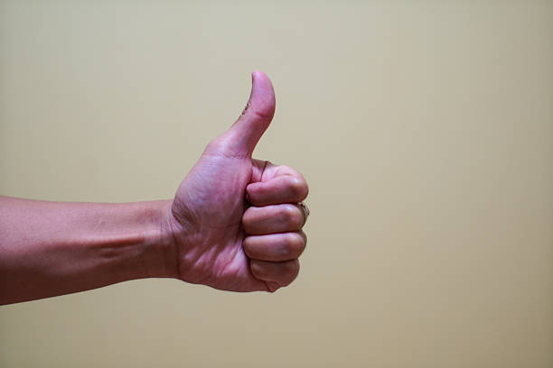 An arm gesturing a thumbs up for encouragement on an isolated white background