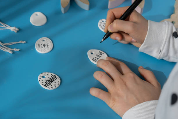 istock Workshop writing word BELIEVE on EASTER clay egg Creator is using white air dry clay for making decor to EASTER holiday. Creating hobby recreation activity that involves fingers. DIY crafting 2188806993