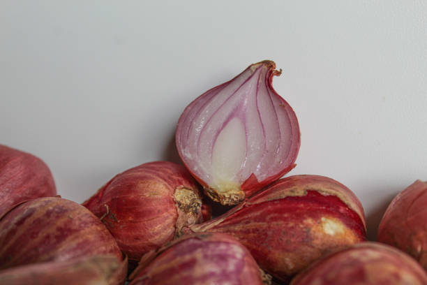 Unpeeled halved red shallot on white background